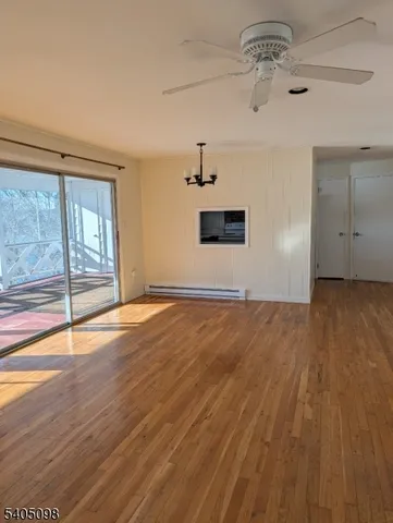 an empty room with wooden floor chandelier fan and windows