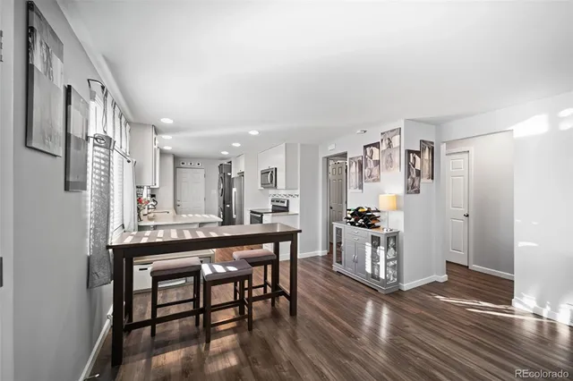 a kitchen with stainless steel appliances a dining table chairs and wooden floor