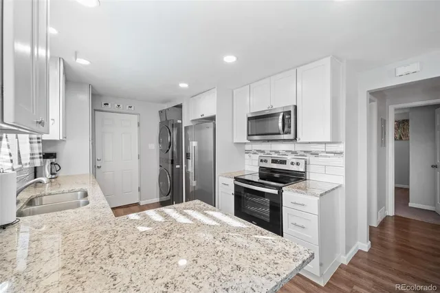 a kitchen with granite countertop a refrigerator stove and sink