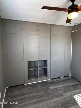 an empty room with wooden floor closet and windows