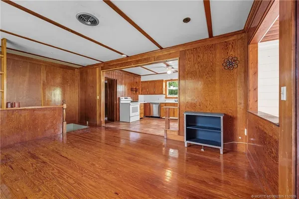 a view of empty room with wooden floor and fan