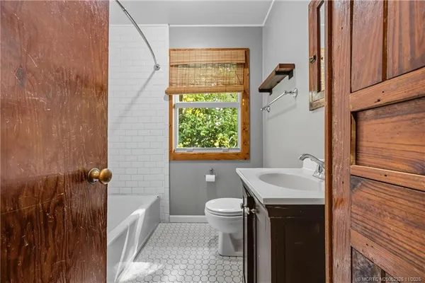 an empty room with windows wooden floor and front door