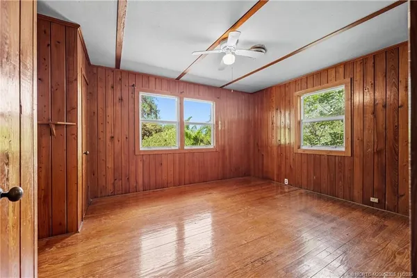an empty room with wooden floor fan and windows
