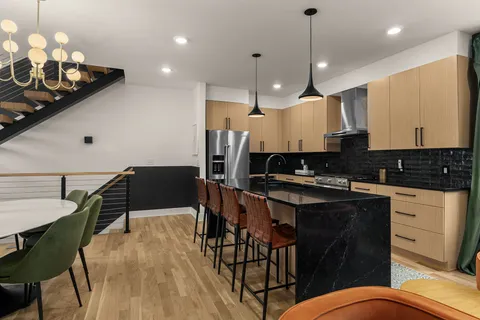 a kitchen with stainless steel appliances kitchen island granite countertop a stove a sink a dining table and chairs with wooden floor