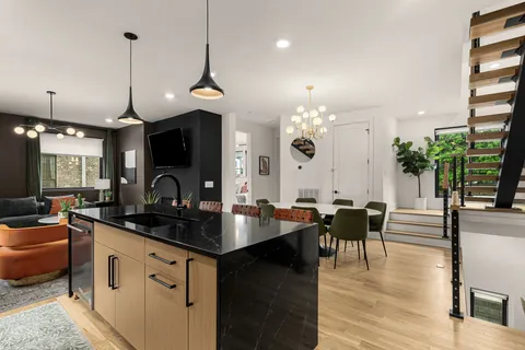 a kitchen with granite countertop a stove a sink a dining table and chairs with wooden floor