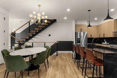 a kitchen with stainless steel appliances kitchen island granite countertop a dining table chairs and a refrigerator