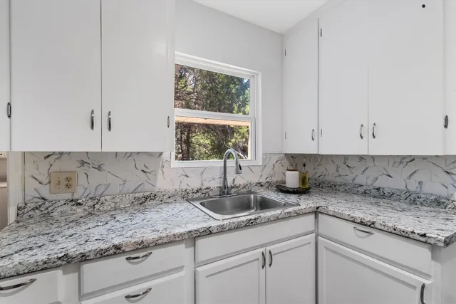 a kitchen with granite countertop white cabinets and a sink