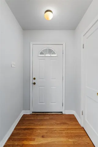 a view of an empty room with window and wooden floor