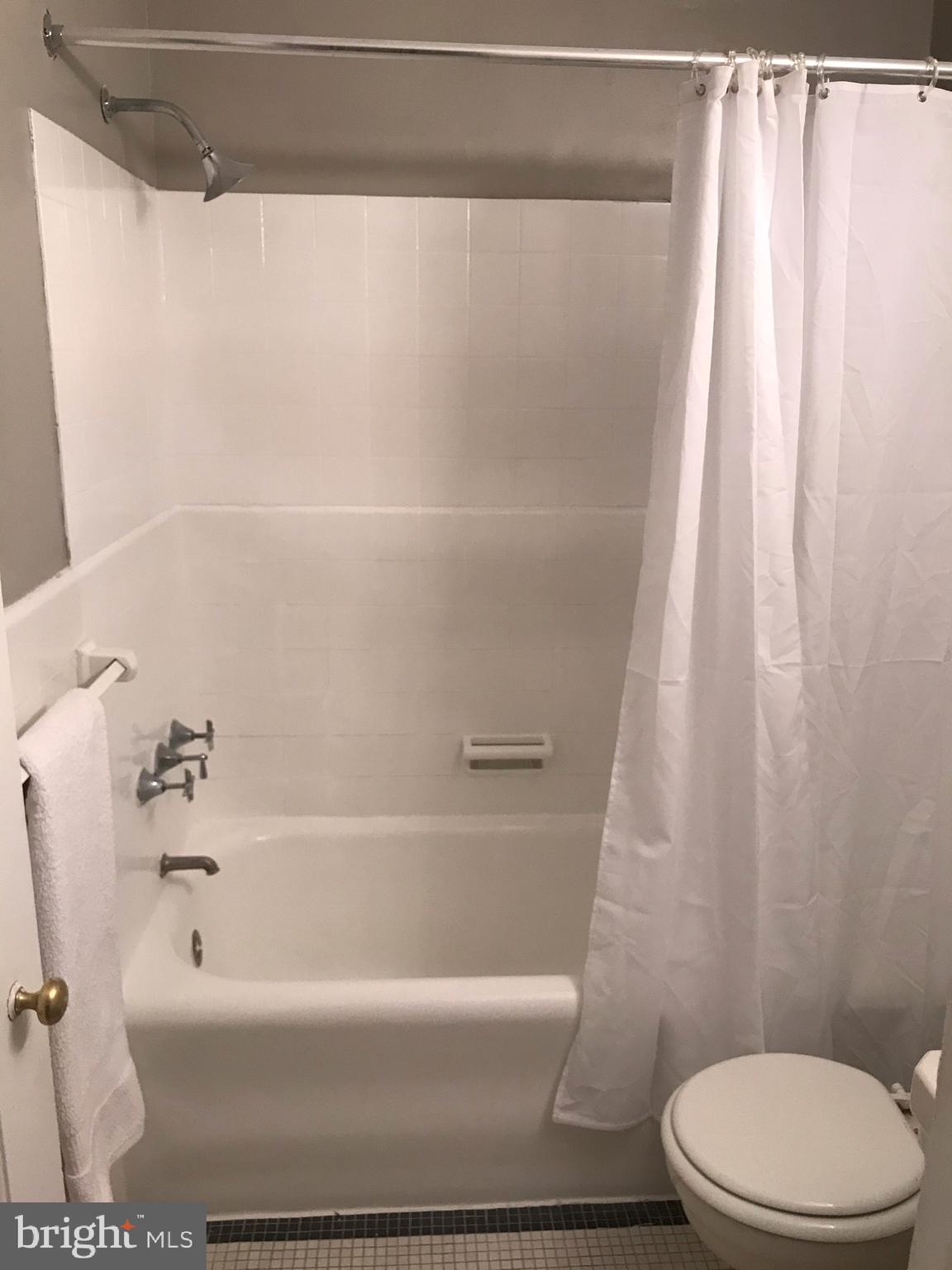 2031 Locust Street, Unit 1404 Philadelphia, PA 19103 - Photo 13 of 20 a white bath tub sitting next to a white toilet and curtain