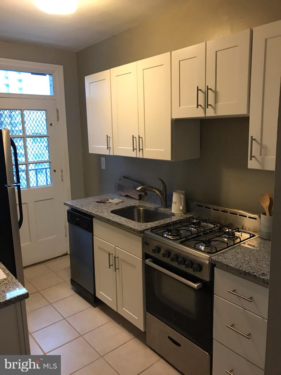 2031 Locust Street, Unit 1404 Philadelphia, PA 19103 - Photo 4 of 20 a kitchen with stainless steel appliances granite countertop a stove a sink and a microwave