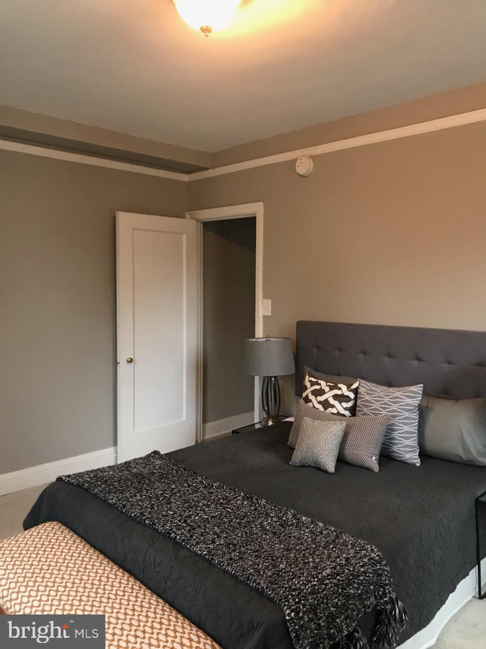 2031 Locust Street, Unit 1404 Philadelphia, PA 19103 - Photo 9 of 20 a bedroom with a bed and a lamp on dresser