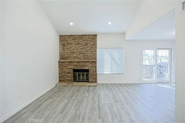 an empty room with wooden floor fireplace and windows