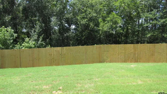 a view of backyard with wooden fence