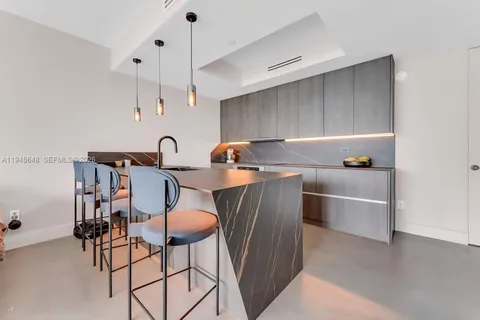 a kitchen with stainless steel appliances granite countertop a sink a stove a dining table and chairs with wooden floor