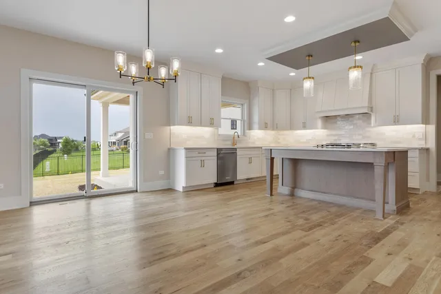 a large kitchen with granite countertop a large counter top a sink stainless steel appliances and cabinets