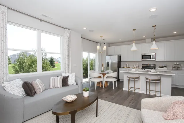a living room with furniture kitchen and a large window