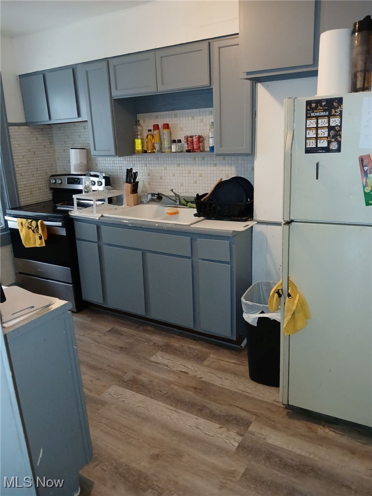 3633 Cedarbrook Road Cleveland, OH 44118 - Photo 14 of 19 Kitchen with dark wood-type flooring, white refrigerator, sink, backsplash, and stainless steel electric stove