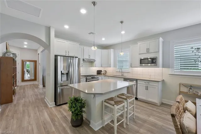 a kitchen with stainless steel appliances granite countertop a refrigerator a sink dishwasher and white cabinets with wooden floor