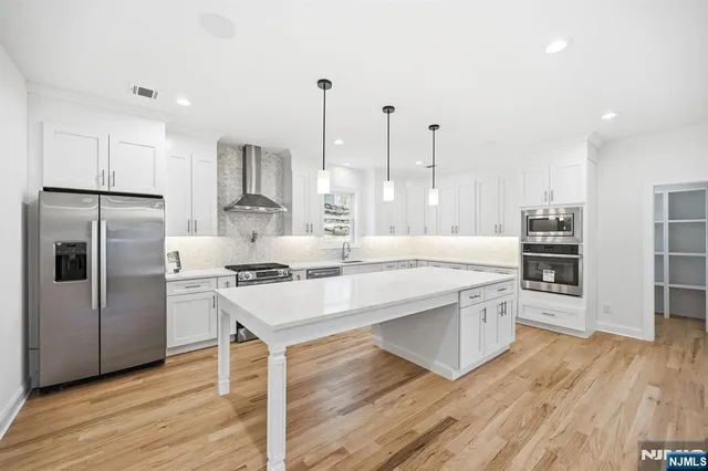 a open kitchen with stainless steel appliances granite countertop a stove refrigerator and a wooden floors