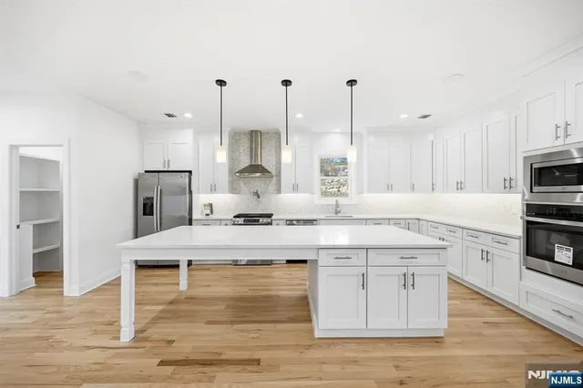 a large kitchen with stainless steel appliances kitchen island granite countertop a stove a sink and white cabinets