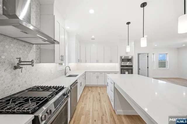 a kitchen with stainless steel appliances granite countertop a stove a sink and a refrigerator