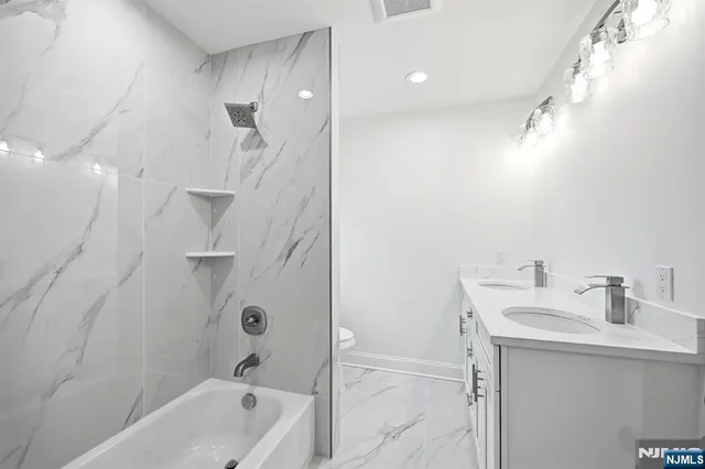 a bathroom with a tub sink vanity and mirror