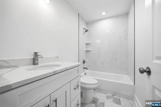 a bathroom with a granite countertop sink a toilet and bathtub