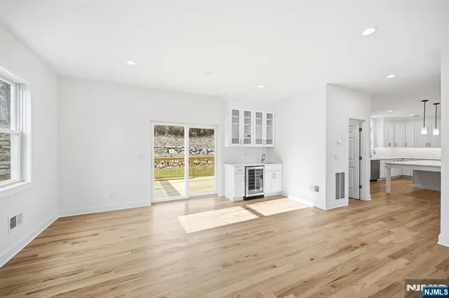 a view of empty room with wooden floor and kitchen view