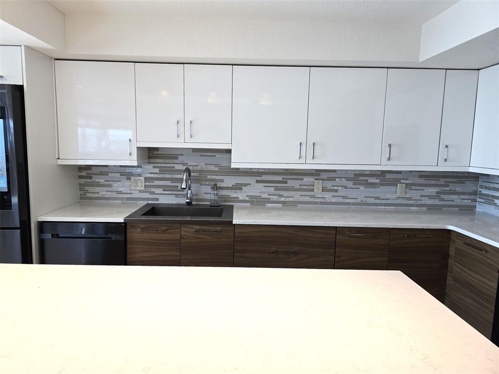 17408 Gulf Boulevard, Unit 1003 Redington Shores, FL 33708 - Photo 17 of 28 a kitchen with stainless steel appliances granite countertop a stove a sink and white cabinets