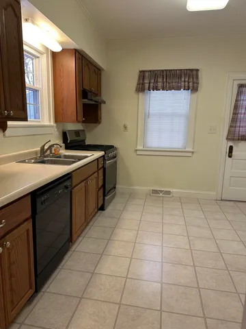 a kitchen with a sink a stove cabinets and a window