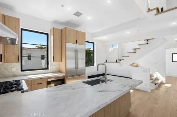 a kitchen with stainless steel appliances kitchen island granite countertop a sink and a refrigerator