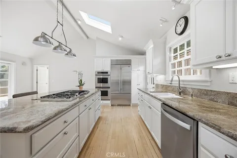 a large kitchen with granite countertop a sink a stove and cabinets