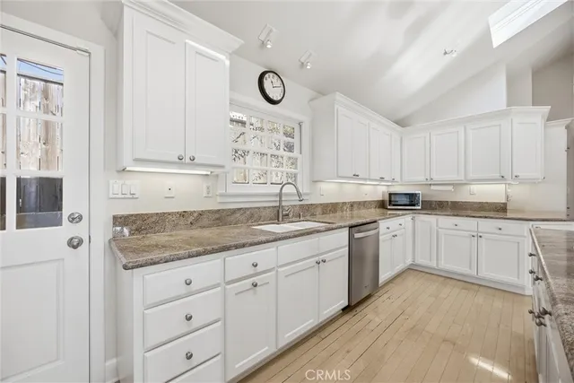 a kitchen with granite countertop white cabinets white stainless steel appliances with a sink and dishwasher