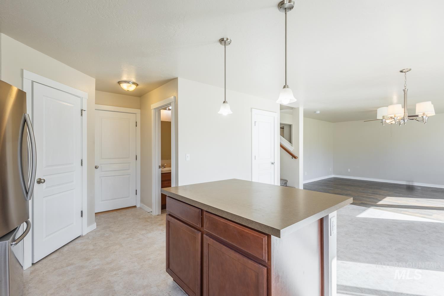 14253 Moreno Drive Caldwell, ID 83607 - Photo 13 of 48 Kitchen island featuring a solid surface countertop, rich wood-finish cabinetry, and brushed nickel pendant lighting