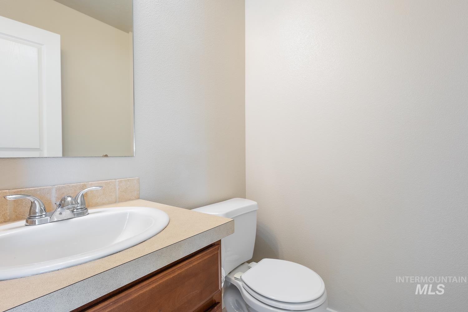 14253 Moreno Drive Caldwell, ID 83607 - Photo 15 of 48 Bathroom vanity featuring a light-colored countertop with an integrated white sink, chrome faucet, and wood-finish cabinetry
