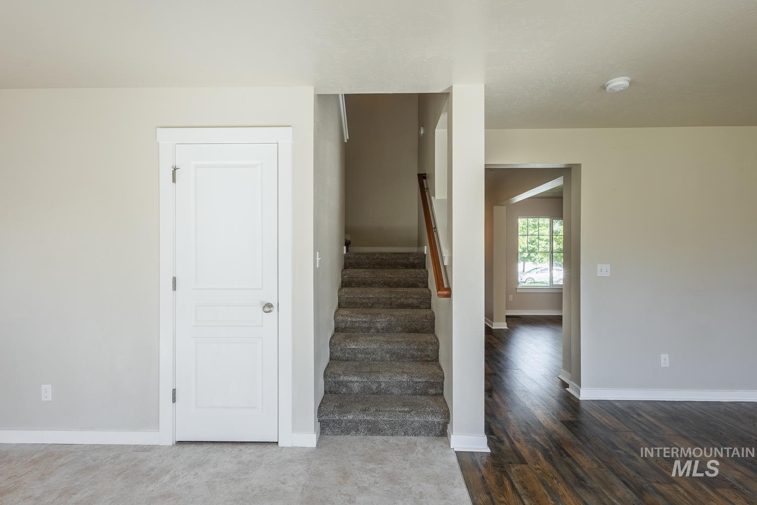 14253 Moreno Drive Caldwell, ID 83607 - Photo 16 of 48 Entryway featuring a paneled door with brushed nickel hardware, carpeted stairs with a wood handrail, and a spacious archway