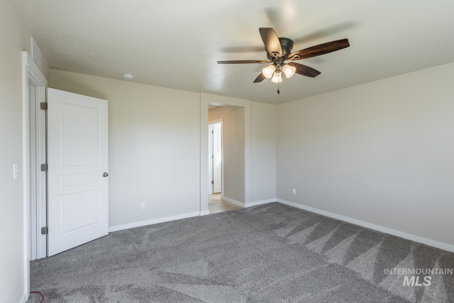 14253 Moreno Drive Caldwell, ID 83607 - Photo 18 of 48 Spacious room featuring neutral wall tones, gray patterned carpeting, and a dark-toned ceiling fan with integrated lighting