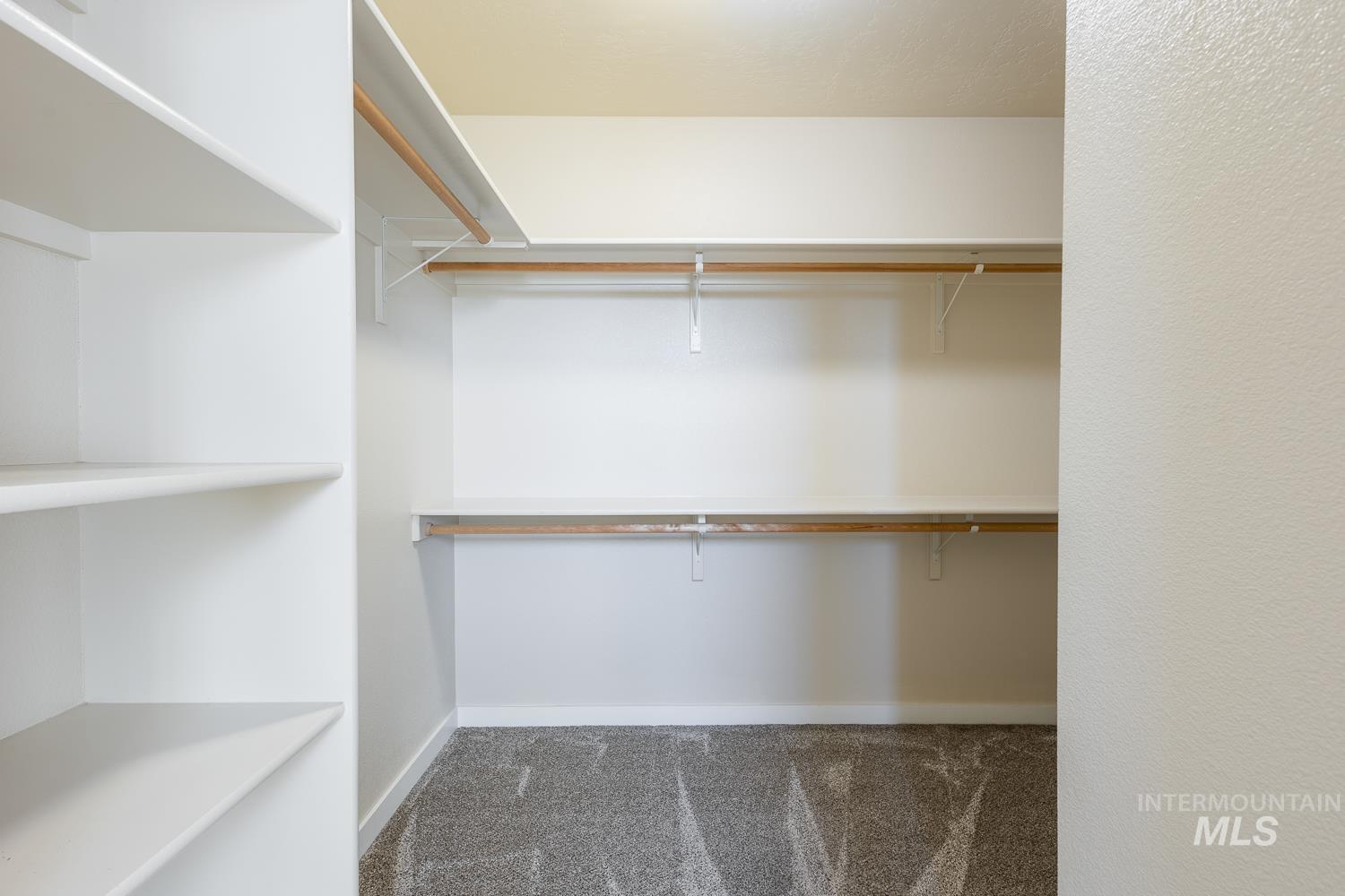 14253 Moreno Drive Caldwell, ID 83607 - Photo 23 of 48 Spacious closet featuring white built-in shelving, dual hanging rods, and neutral-toned carpeting