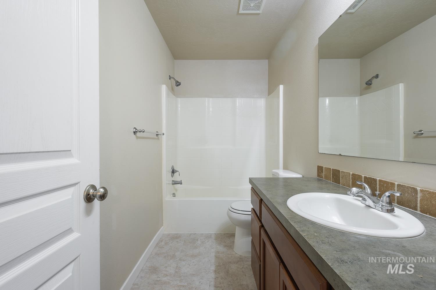 14253 Moreno Drive Caldwell, ID 83607 - Photo 27 of 48 Full bathroom featuring a single vanity with an integrated sink, a dark countertop, and a wood-finish cabinet