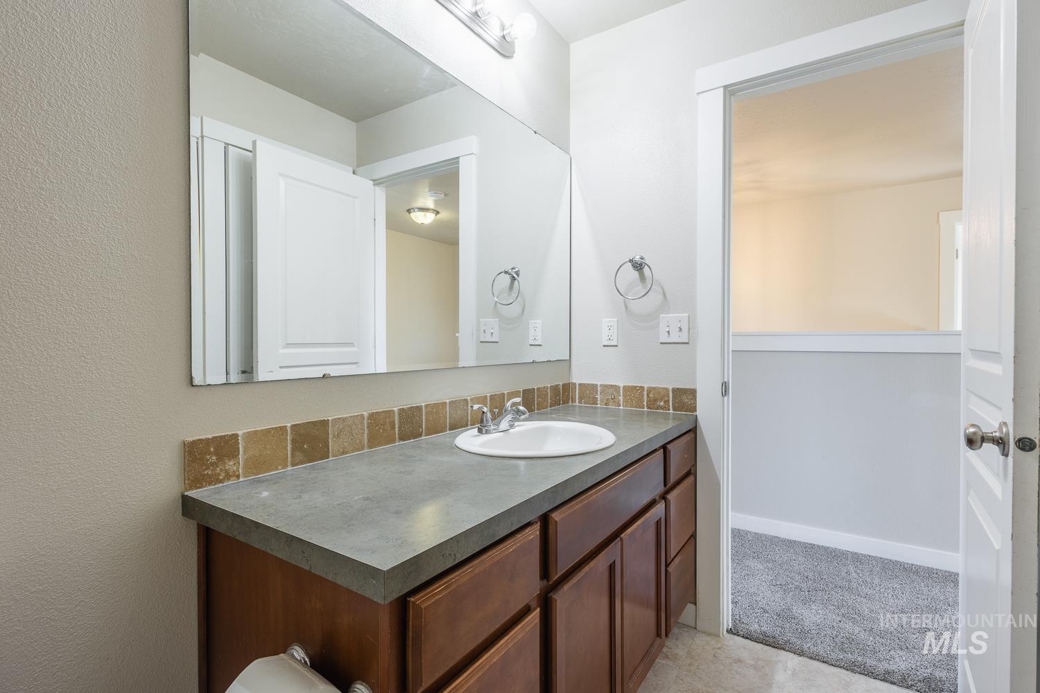 14253 Moreno Drive Caldwell, ID 83607 - Photo 28 of 48 Bathroom vanity featuring a single basin sink, large wall-mounted mirror, and a tile backsplash