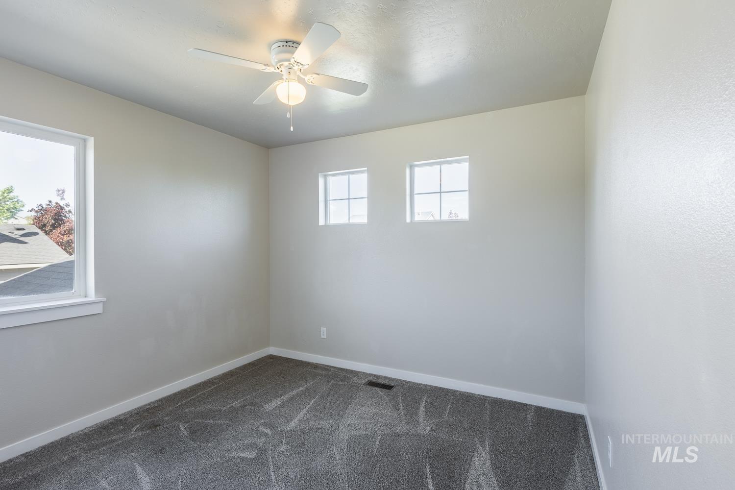 14253 Moreno Drive Caldwell, ID 83607 - Photo 29 of 48 Carpeted room featuring a ceiling fan with light, one large window, and two smaller transom windows