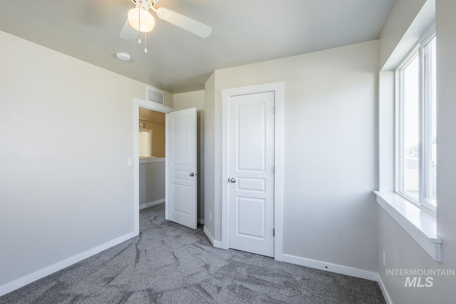 14253 Moreno Drive Caldwell, ID 83607 - Photo 30 of 48 Carpeted room featuring a ceiling fan, a window with white trim, and a built-in closet with an open doorway