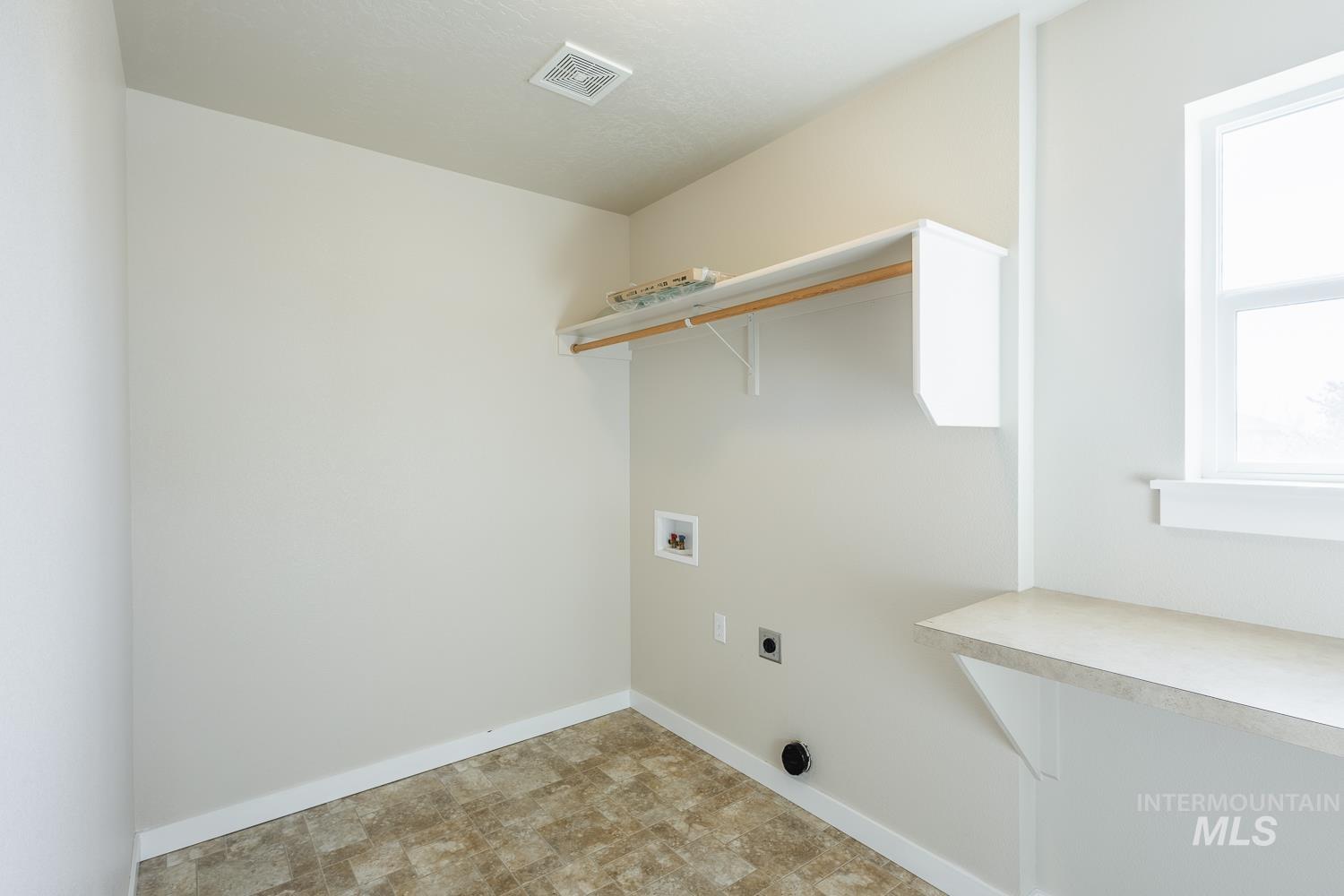 14253 Moreno Drive Caldwell, ID 83607 - Photo 31 of 48 Utility room featuring a window, built-in shelving, a hanging rod, a countertop, and durable flooring
