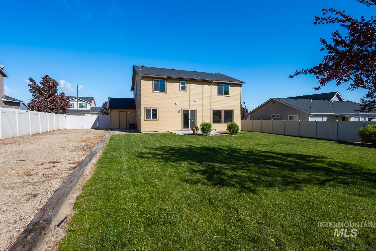 14253 Moreno Drive Caldwell, ID 83607 - Photo 37 of 48 Expansive backyard featuring a large green lawn, a concrete patio, and a two-story residence with light-colored siding and a dark shingle roof