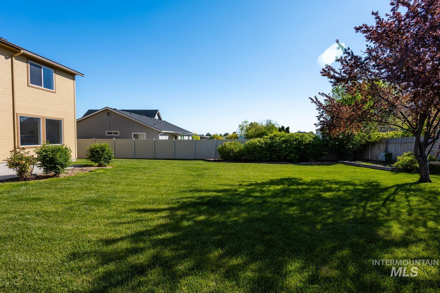14253 Moreno Drive Caldwell, ID 83607 - Photo 38 of 48 Expansive rear yard featuring a large green lawn, perimeter shrubs, and a mature tree