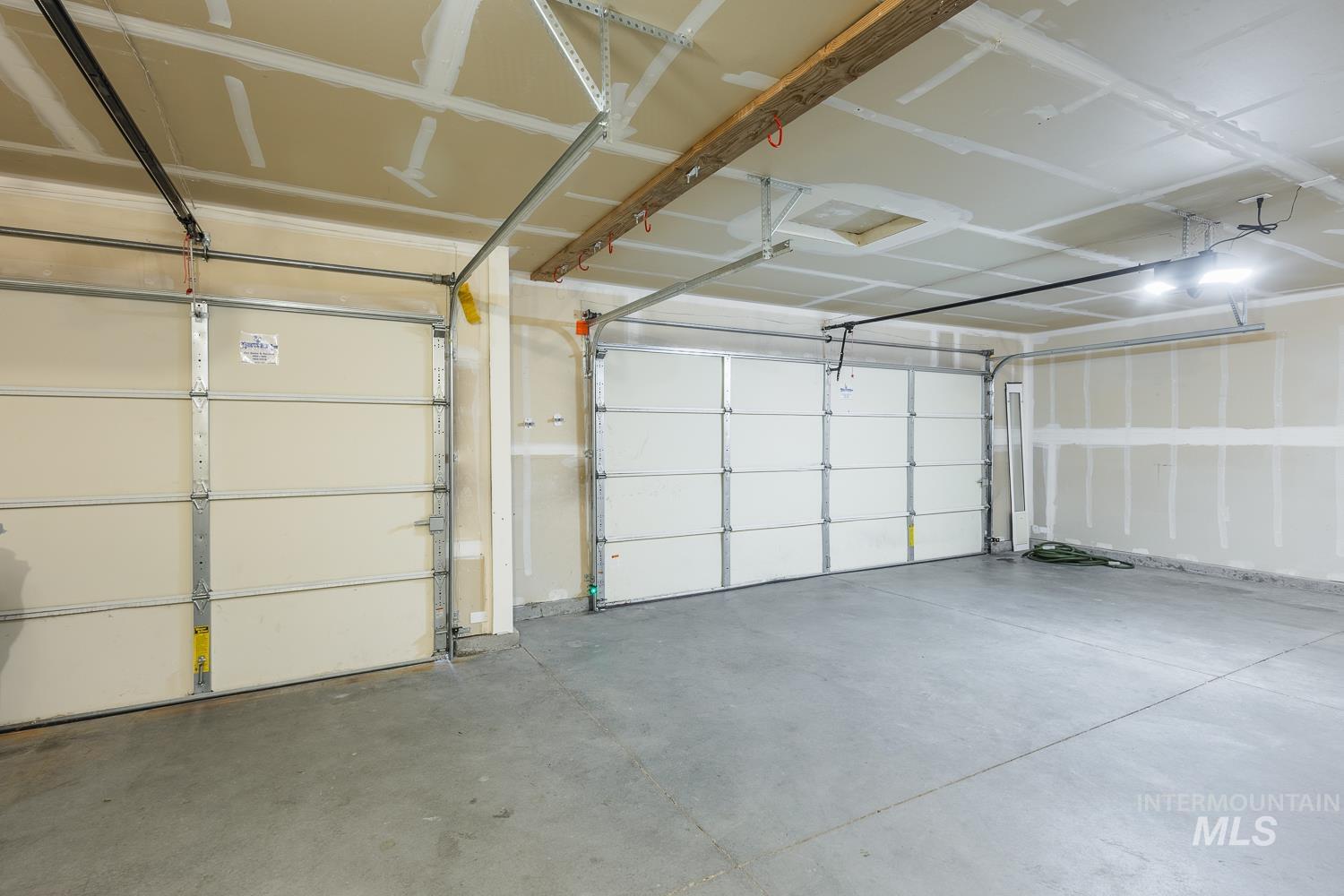 14253 Moreno Drive Caldwell, ID 83607 - Photo 42 of 48 Spacious garage featuring a concrete floor, two sectional garage doors, and overhead lighting