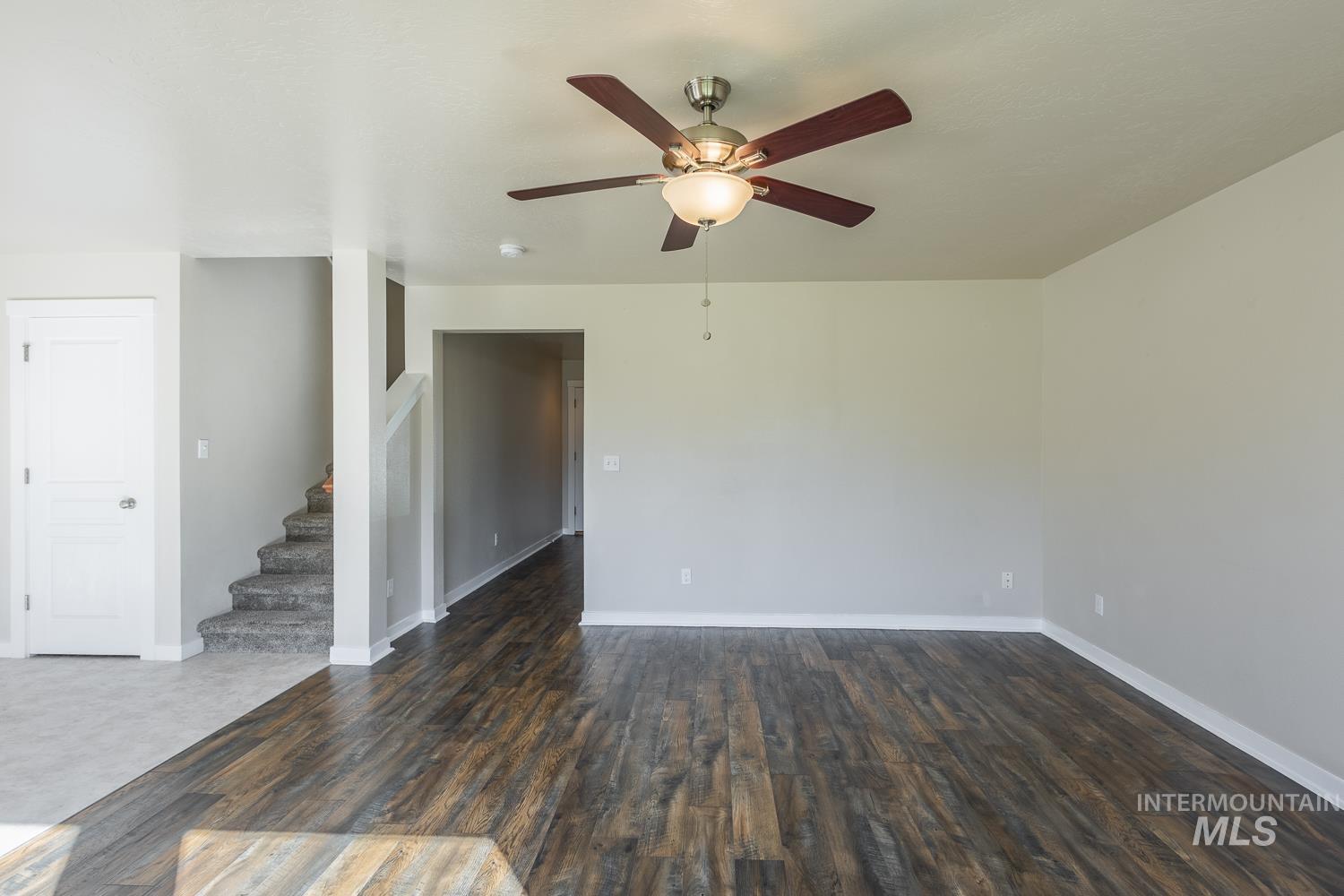14253 Moreno Drive Caldwell, ID 83607 - Photo 10 of 48 Spacious interior featuring wood-finish flooring, a contemporary ceiling fan, light gray wall tones, white trim, and a carpeted staircase