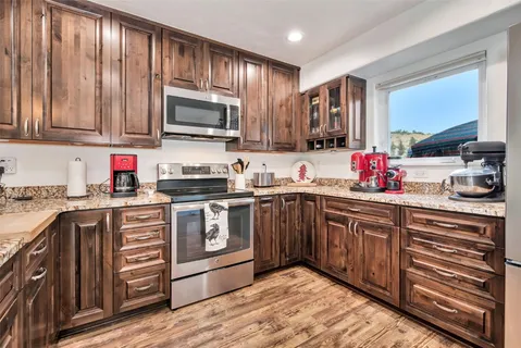a kitchen with stainless steel appliances granite countertop a stove a sink dishwasher and a microwave oven with wooden cabinets