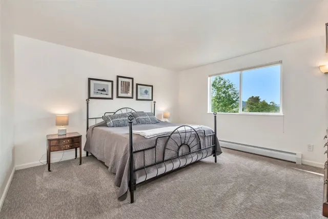 a bedroom with a bed painting on wall and a window