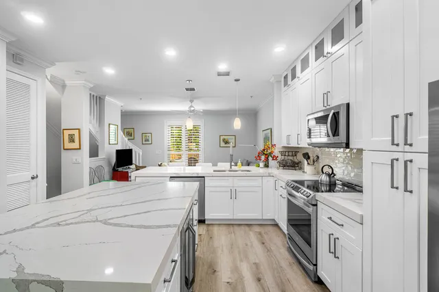 a kitchen with stainless steel appliances kitchen island granite countertop a stove and white cabinets